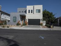 a home sits on the corner of a street with blue bins and gravel driveway