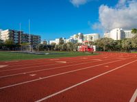 a track and goal area with grass and building towers in the background is shown in this file