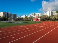 a track and goal area with grass and building towers in the background is shown in this file