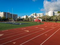 a track and goal area with grass and building towers in the background is shown in this file