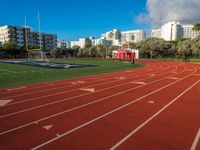 a track and goal area with grass and building towers in the background is shown in this file