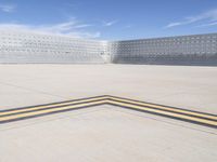 an empty parking lot with large concrete stands in the foreground and a single striped yellow line running across the cement