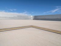 an empty parking lot with large concrete stands in the foreground and a single striped yellow line running across the cement