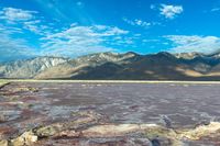 mountains covered with vegetation are near a large lake covered in water and some rocks on the bottom of a sandy flat land