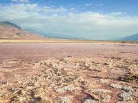 a lake with red and yellow colored water near a mountain area with snow capped mountains