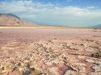 a lake with red and yellow colored water near a mountain area with snow capped mountains