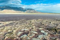 the dry and colorful ground in a desert plain area is mostly barren, and has very little vegetation