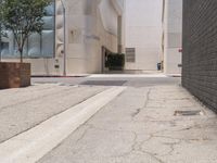 a street corner with a paved sidewalk and some tall buildings in the background of this photo