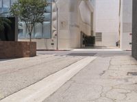 a street corner with a paved sidewalk and some tall buildings in the background of this photo