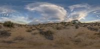 a view of a large desert with a building in the distance with some cloudy skies above