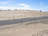 a paved beach with a fence in front of it and the ocean in the distance