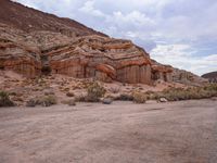 the rocks are red with white, orange and brown formations of a mountain range in the background