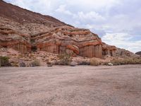 the rocks are red with white, orange and brown formations of a mountain range in the background