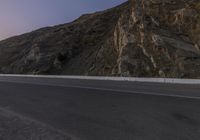 a lone motorcycle is parked near the mountain side of a highway in california's desert