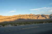 a lone desert highway with hills in the background under a blue sky and cloudless sky