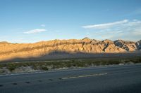 a lone desert highway with hills in the background under a blue sky and cloudless sky