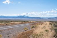 a long highway running through the desert with mountains in the background behind it with clouds