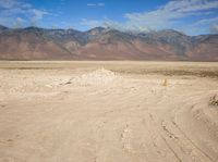 a barren area with mountains in the distance, a sign pointing to a road way