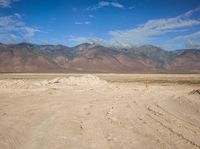 a barren area with mountains in the distance, a sign pointing to a road way