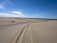 a paved beach with a fence in front of it and the ocean in the distance