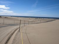 a paved beach with a fence in front of it and the ocean in the distance