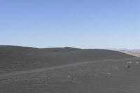 two people are riding horses in a big expanse of dirt covered landscape, and another person on the other side