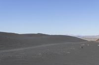 two people are riding horses in a big expanse of dirt covered landscape, and another person on the other side