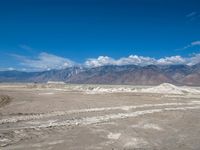 mountains are seen in the distance from this desert scene, the sky appears to be filled with clouds