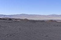 a large number of rocks in the desert with mountains and trees in the back ground