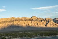 a mountain range in the desert in front of some distant mountains and blue sky below