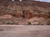 there are two parked motor cycles in the desert field next to the mountain side of the mountain