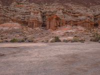 there are two parked motor cycles in the desert field next to the mountain side of the mountain