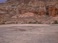 there are two parked motor cycles in the desert field next to the mountain side of the mountain