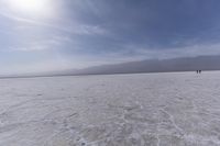 a large barren area with mountains in the distance and a bright sun over the horizon