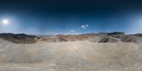 a 360 - view camera shot of the desert with the mountains in the background and a full moon above