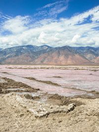 desert area with many mountains and some water in it, including a red lake that is very pink