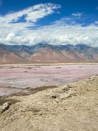 desert area with many mountains and some water in it, including a red lake that is very pink