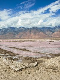 desert area with many mountains and some water in it, including a red lake that is very pink