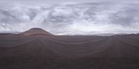 an artistic view of a desert with many mountains in the back ground and a sky with clouds