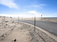 a paved beach with a fence in front of it and the ocean in the distance