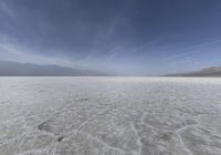 a lone photo in the middle of the desert plain, as seen from below in front of mountains