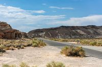 a desert road runs through an abandoned cliff formation in a vast landscape with dry grass