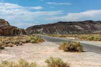 a desert road runs through an abandoned cliff formation in a vast landscape with dry grass