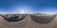 360 - view of road through the middle of desert landscape with sky and mountains in background