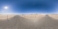 a long empty road stretches into the horizon of desert land and appears to be in a fish eye