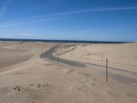 a paved beach with a fence in front of it and the ocean in the distance