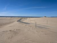 a paved beach with a fence in front of it and the ocean in the distance