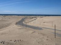 a paved beach with a fence in front of it and the ocean in the distance