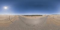 this is an amazing wide angle of a desert road and sky above it and snow capped,