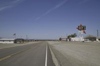 a street in an area of desert with motel signs on the side and a desert road behind